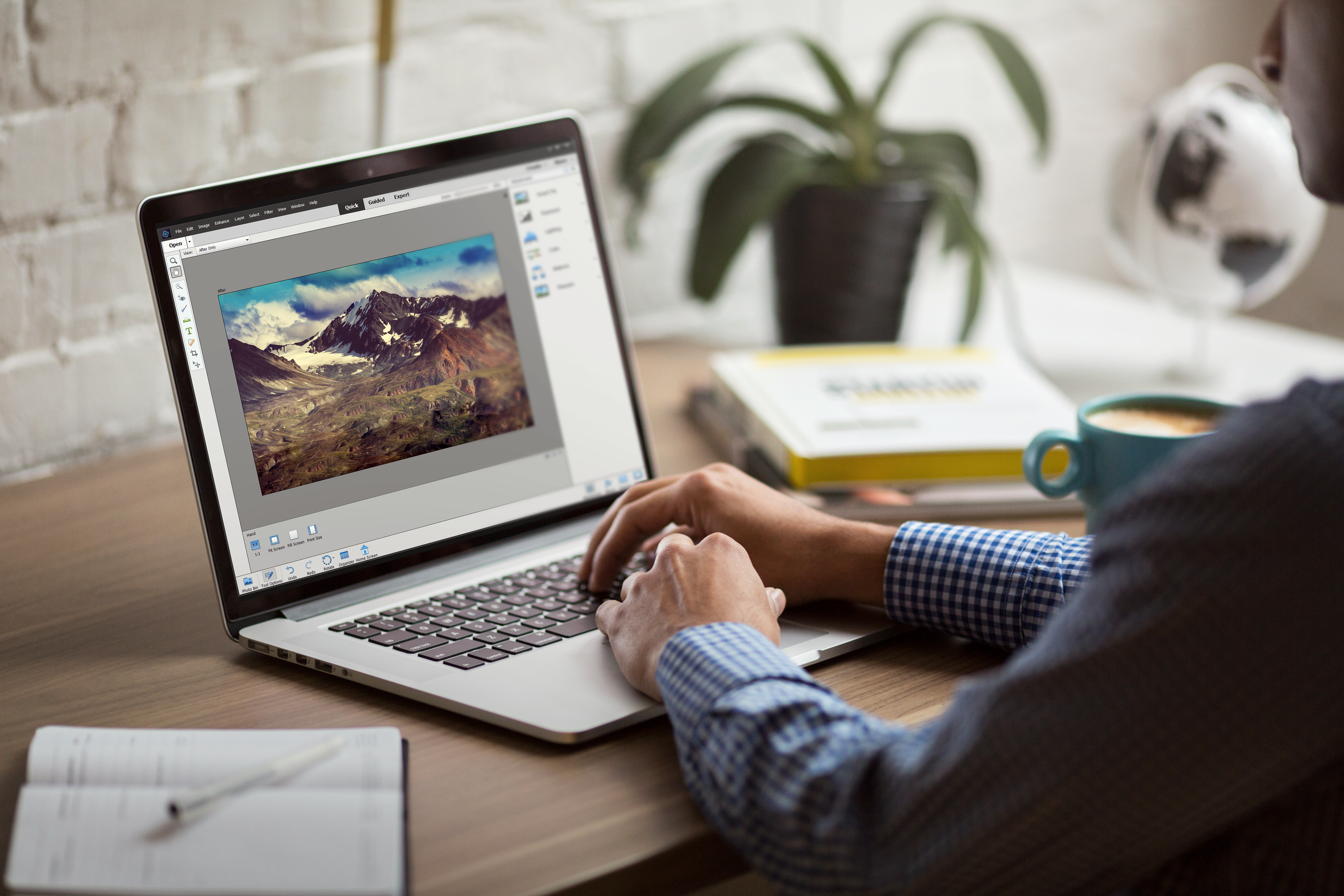 Mies istuu ja käsittelee kuvia Photoshop Elementsillä