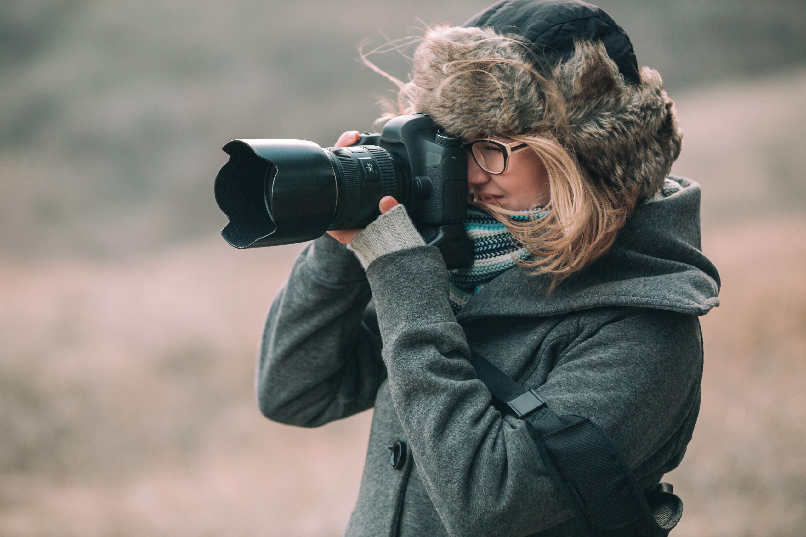 Ung kvinna med vinterjacka med kapuschong och kamera