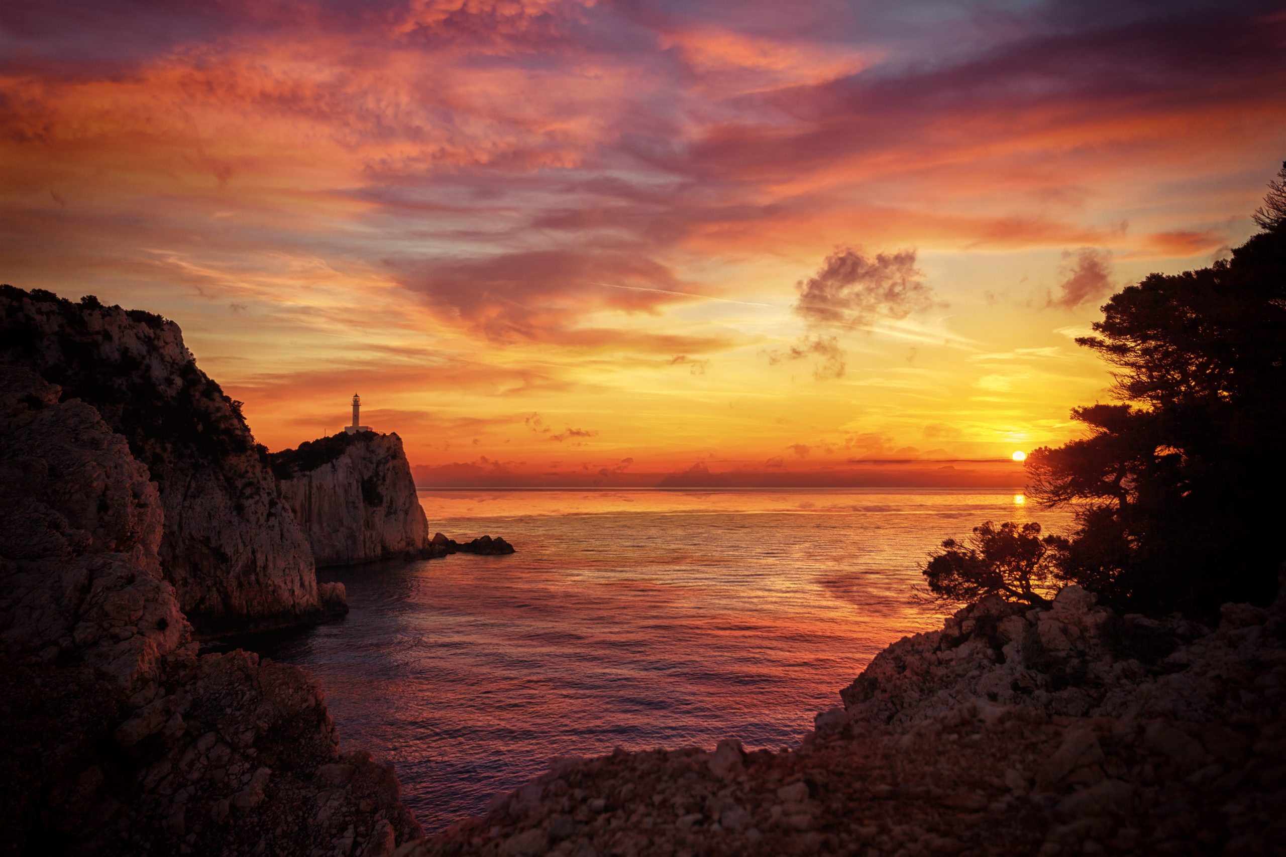 Solnedgång över havet med fyrtorn och klippor