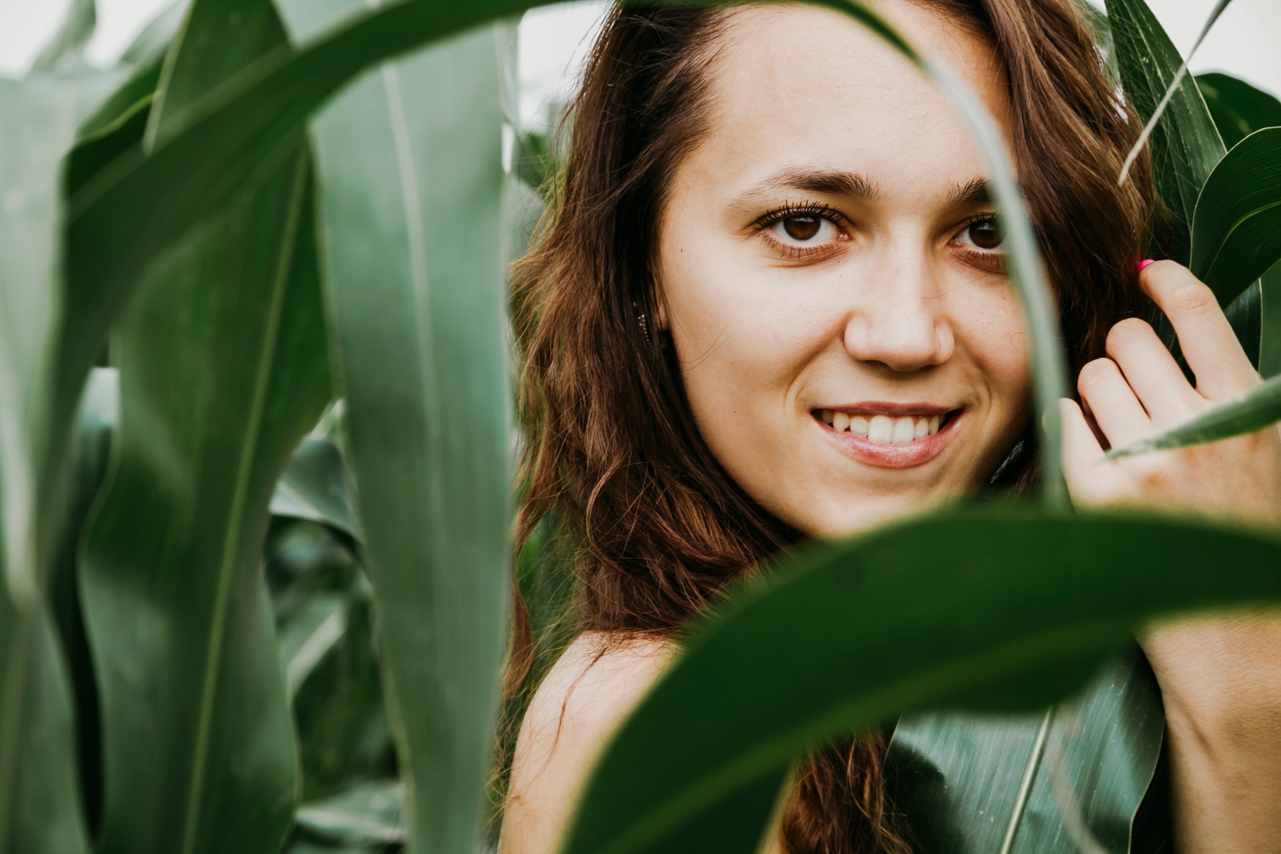 Ung kvinne ser i kamera med palmeblader i forgrunnen