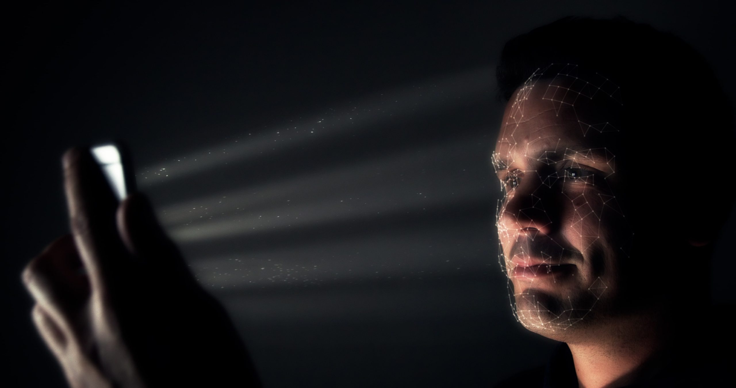 Mies skannaa kasvojaan puhelimella