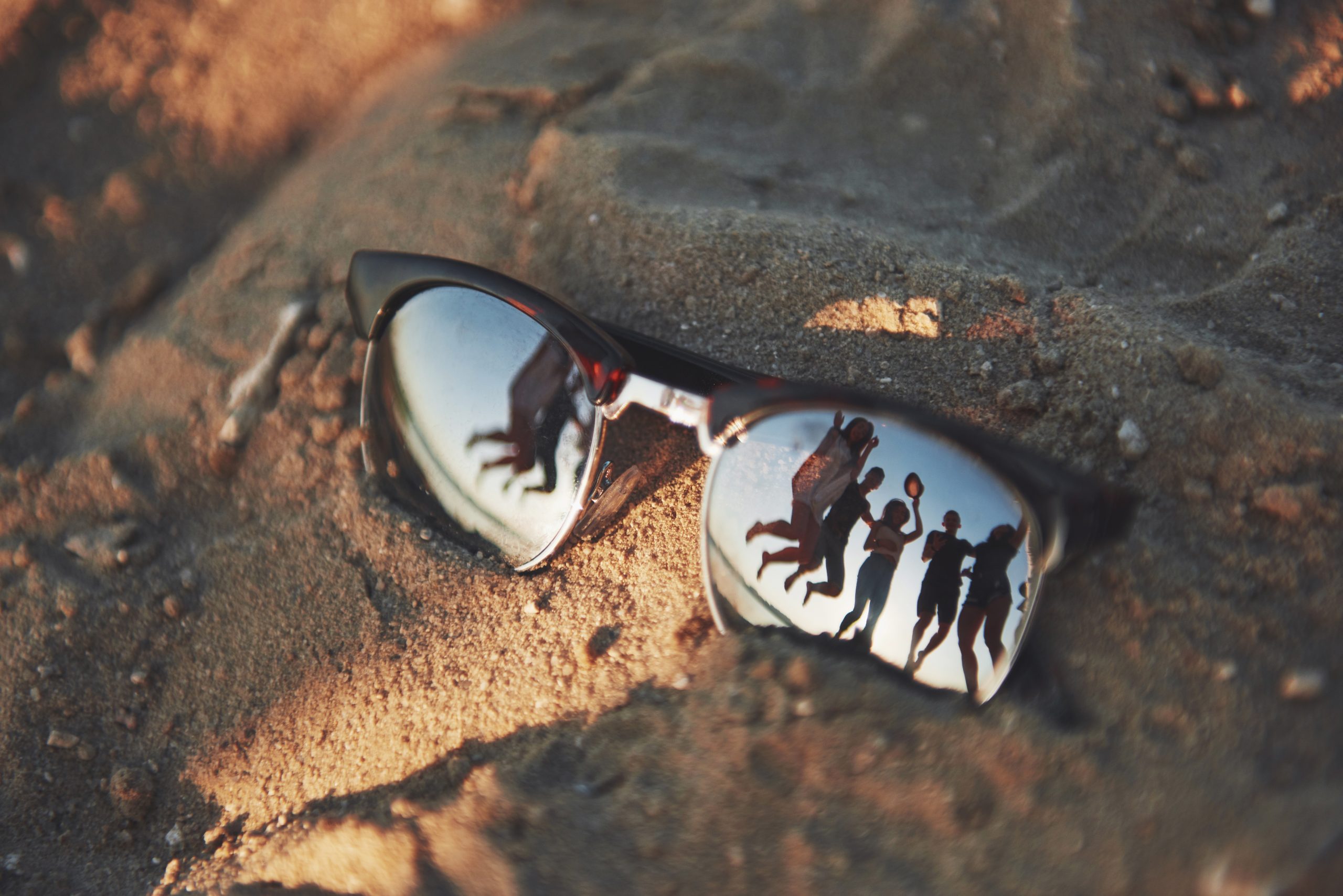 Solbrille med spejling af gruppe der hopper