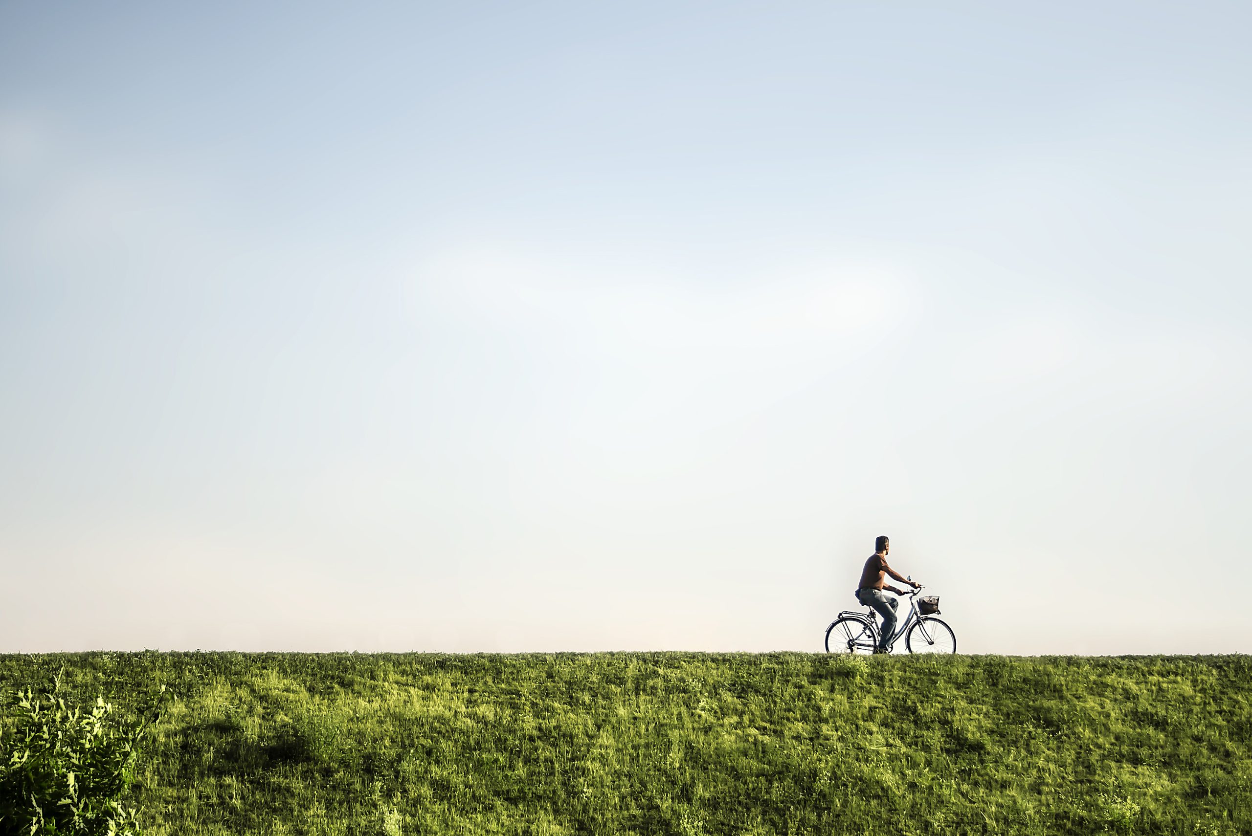 Enkel bild av backe med gräs och man som cyklar förbi