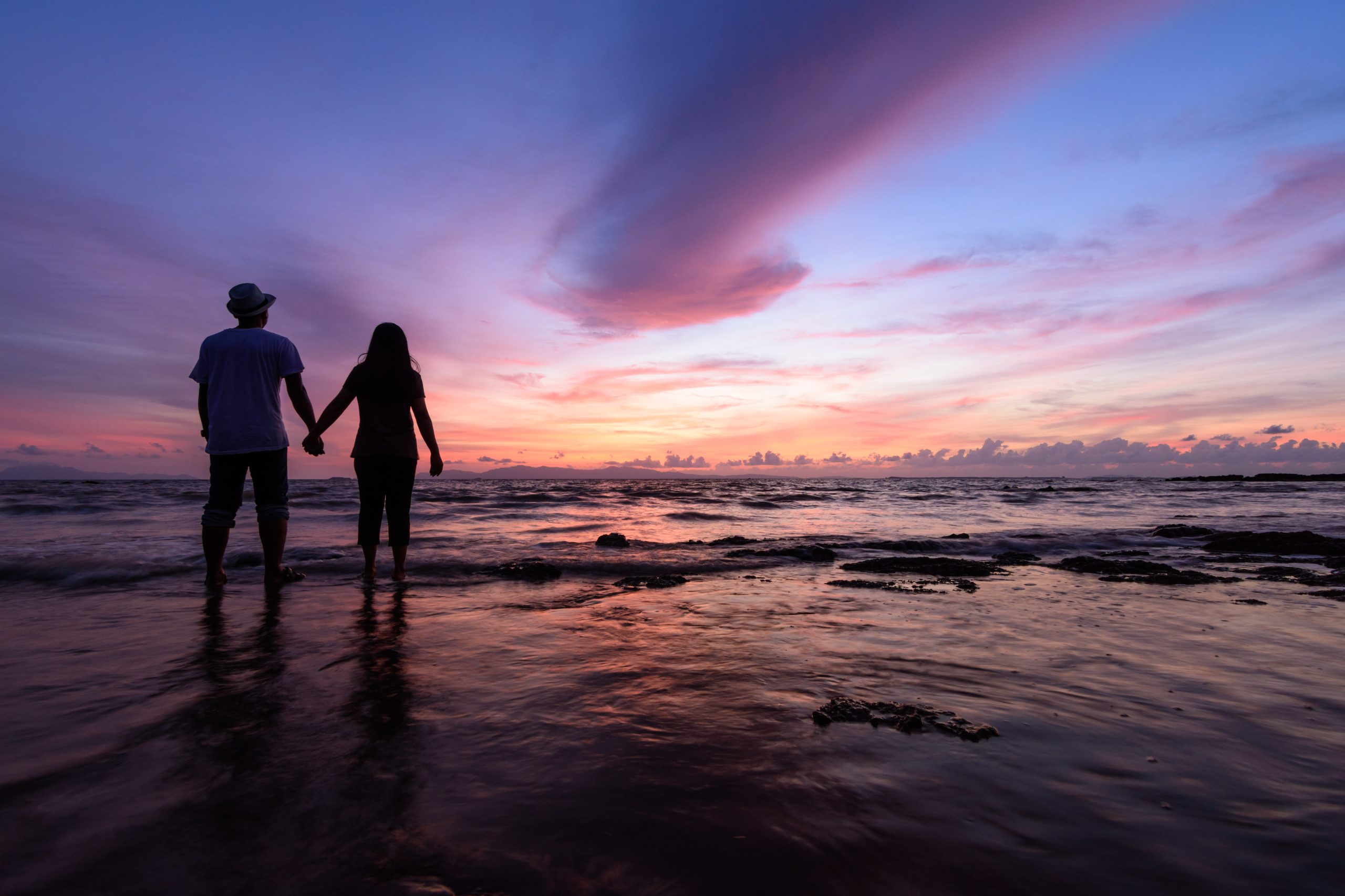 Silhuett av par på stranden i solnedgång