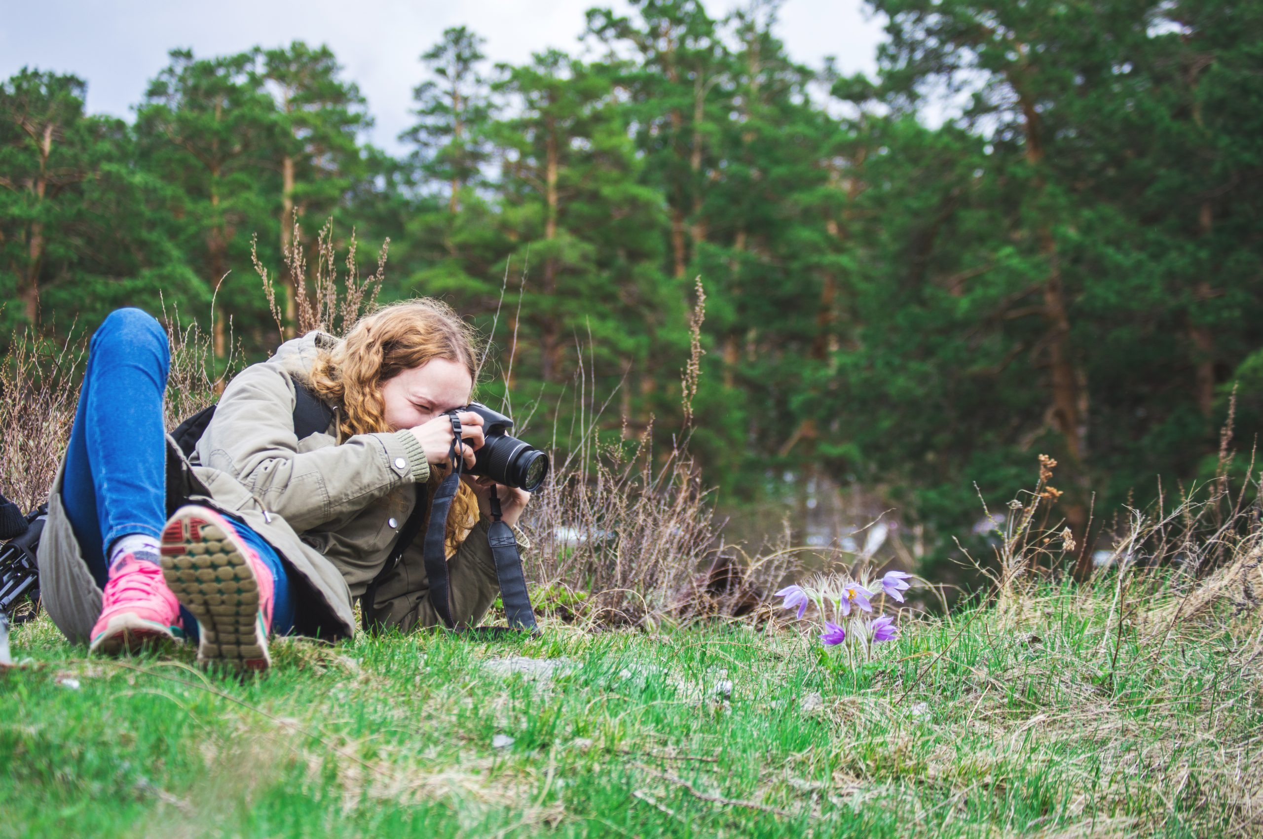 Ung jente fotograferer blomster håndholdt uten kamerastativ
