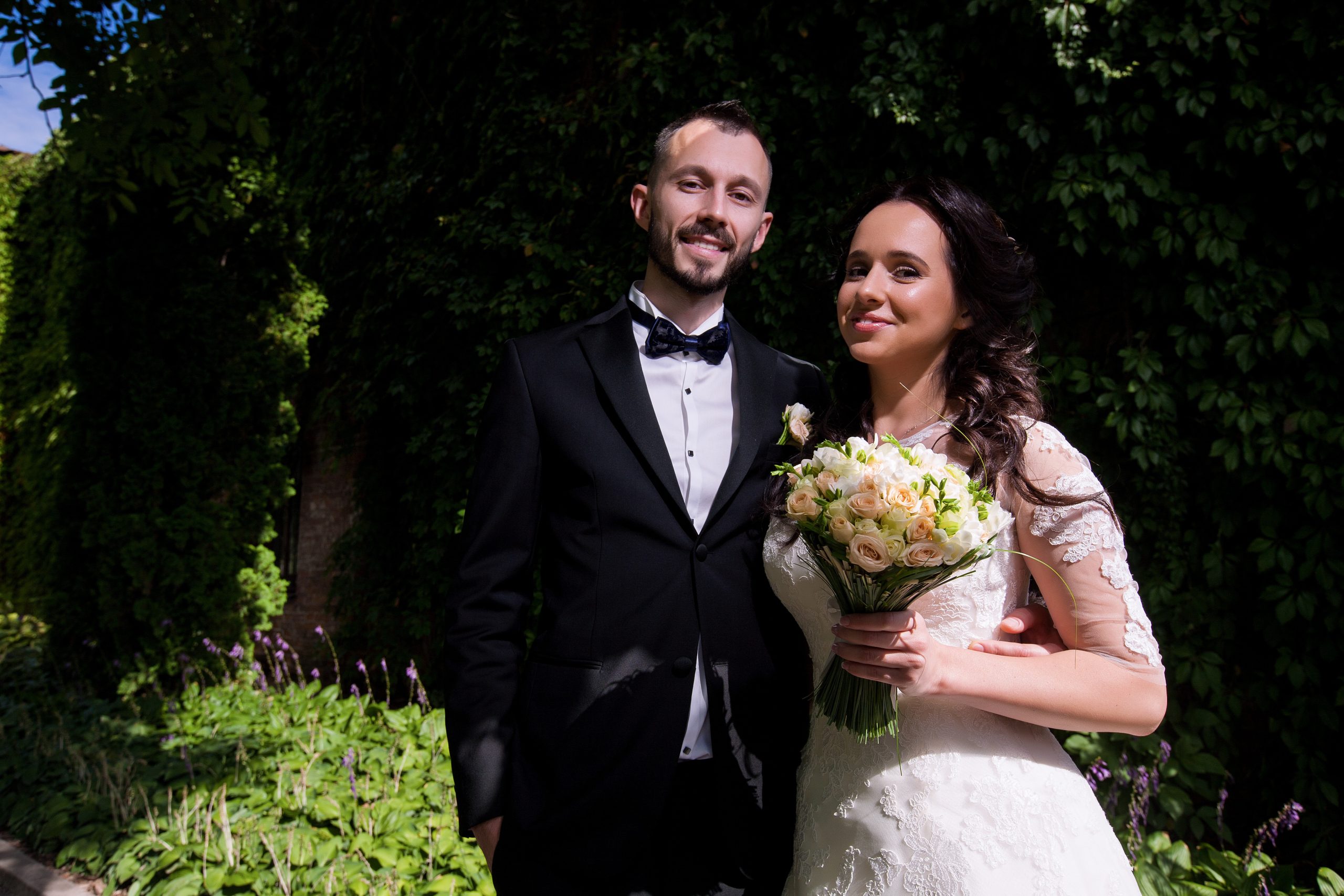 Brudepar fotografert i direkte sollys med rotete bakgrunn