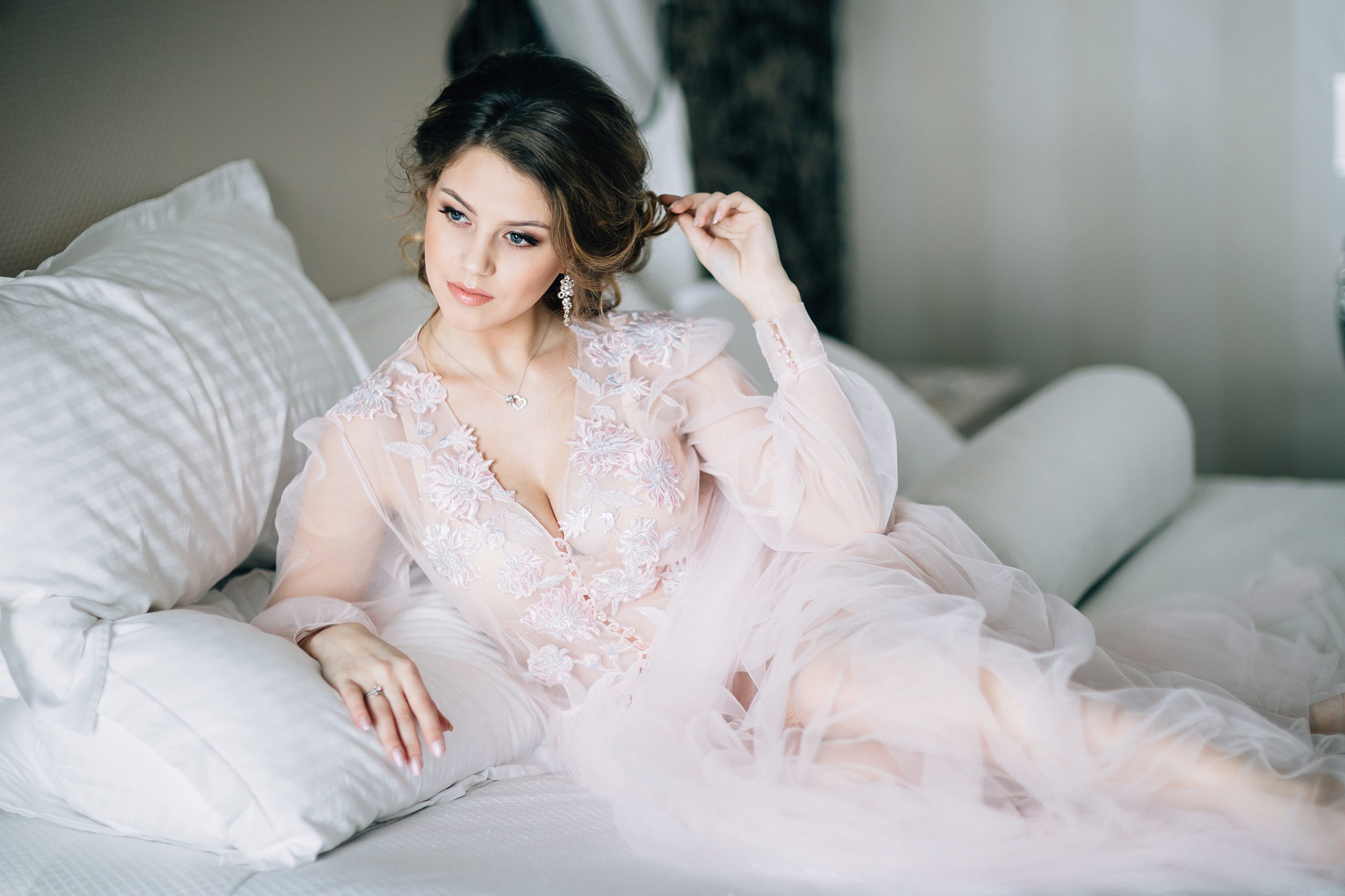 Boudoir-kuvassa nuori nainen makaa sängyllä yllään kevyt asu