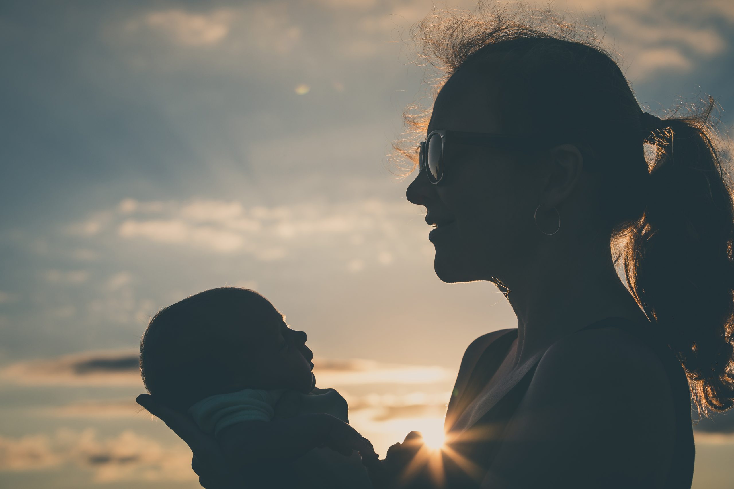 Silhuet af mor og barn i solnedgangen.
