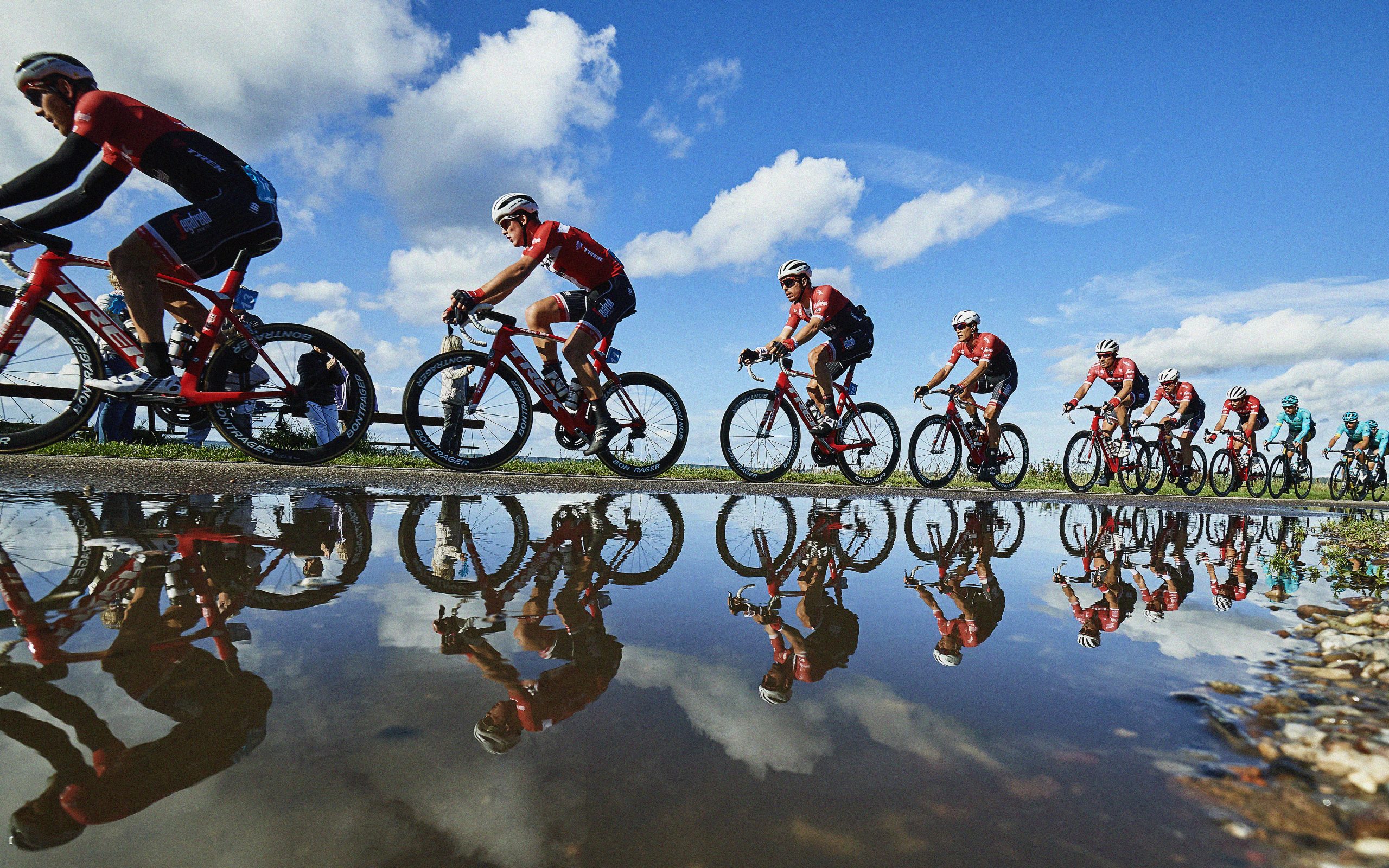 Cykelryttere spejles i vandet.