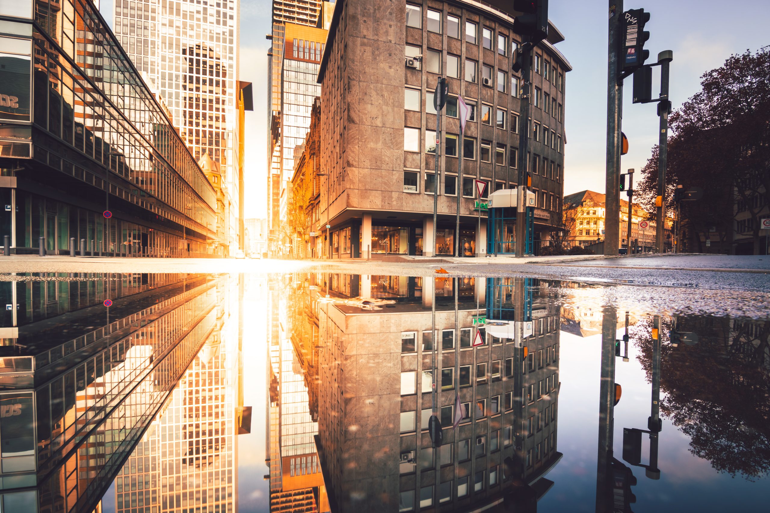 Bygninger reflekteres i vandpyt.