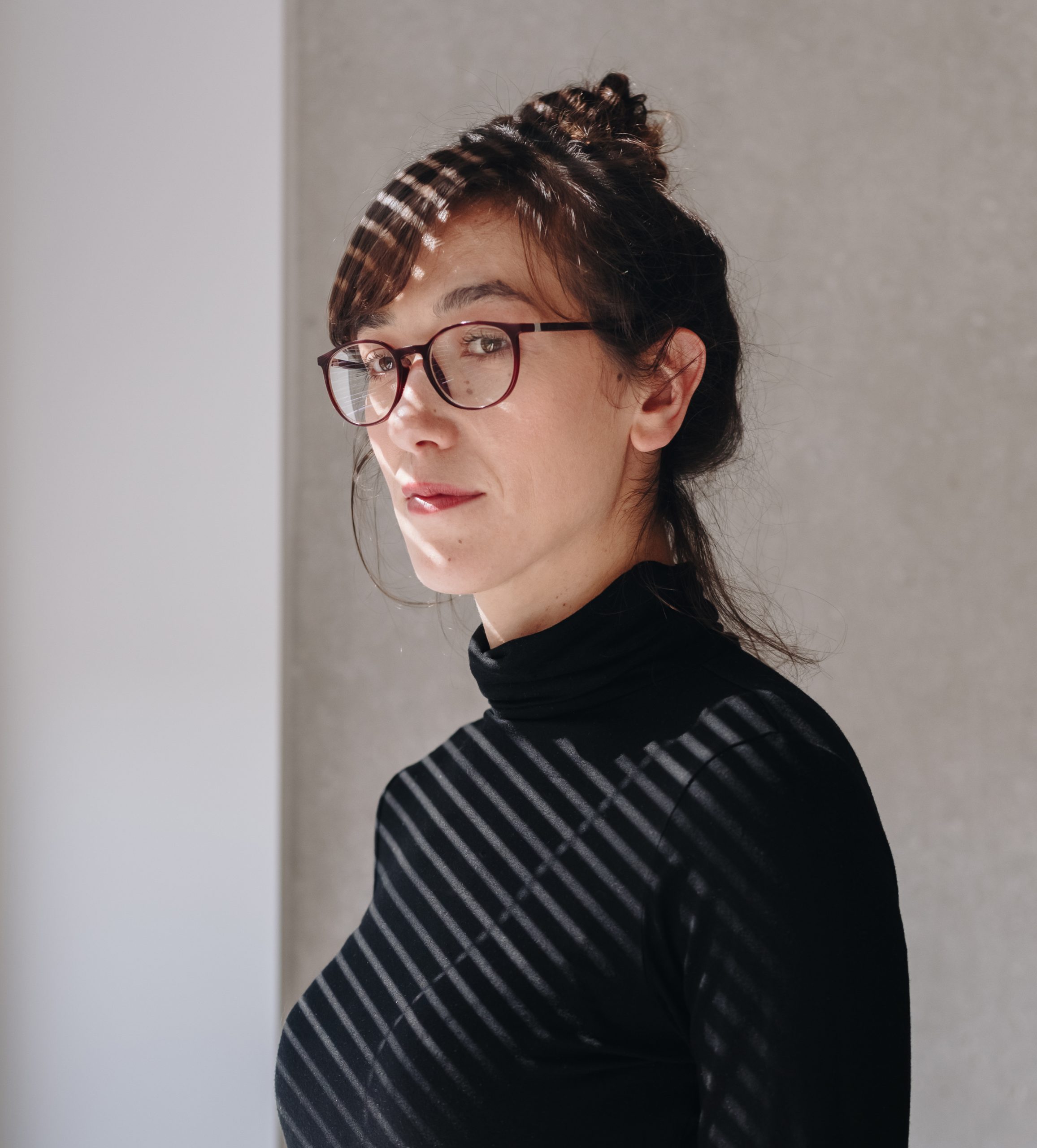 Ung kvinde med briller og opsat hår i skygge fra persienner