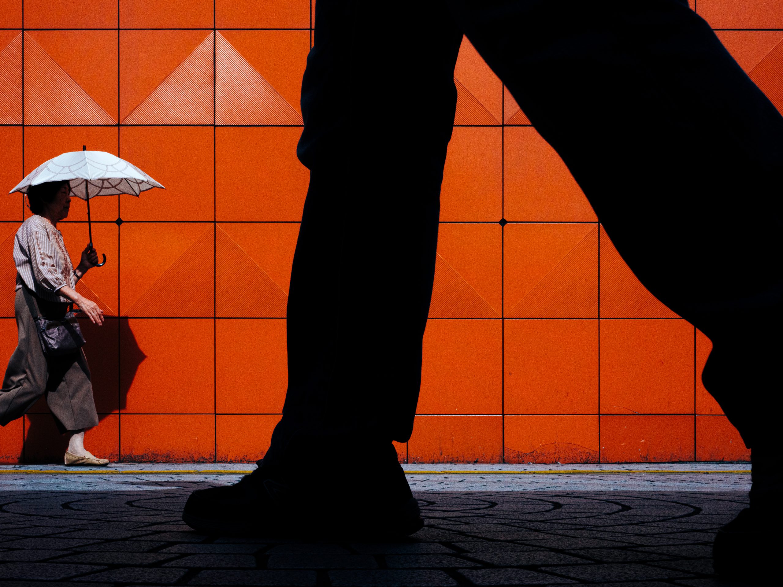 Ben og dame med paraply ved oransje vegg