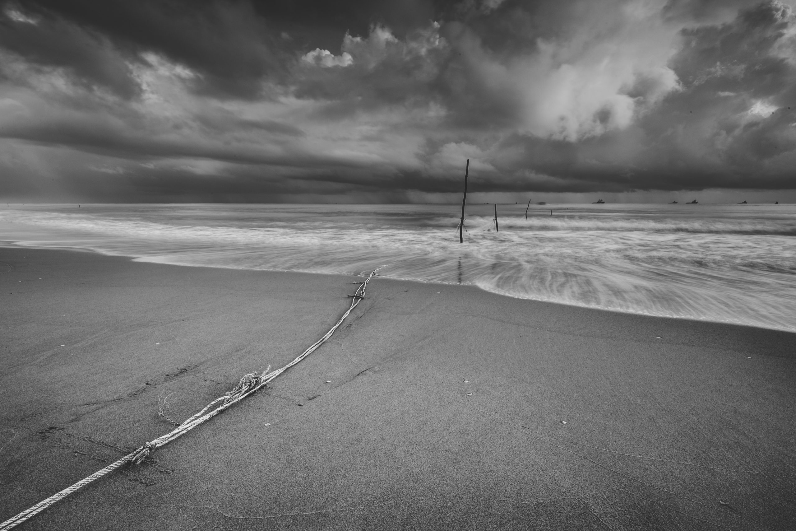 Sort/hvitt-bilde av overskyet strand.