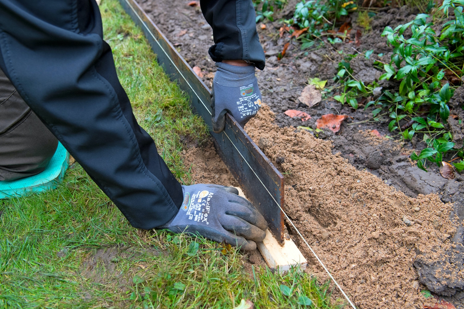 Stålkanter til bede: Placér den første jernkant på en træklods