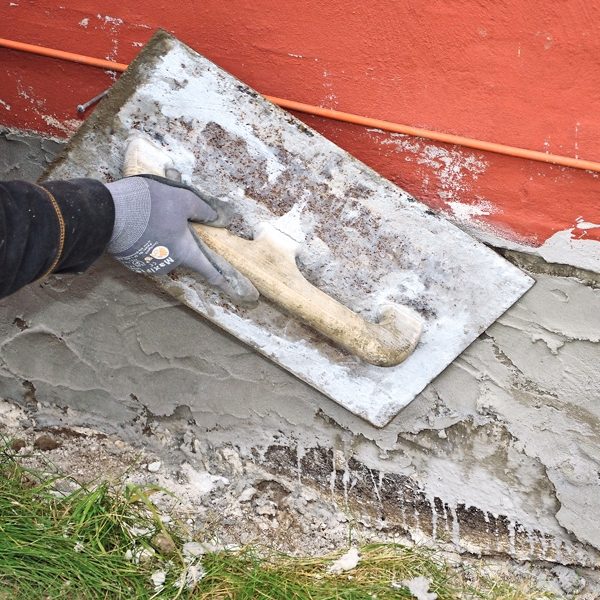 Reparere grunnmur: Første lag røres opp til en grøtaktig konsistens og kastes på med en murskje