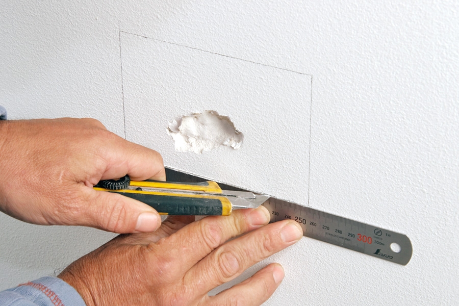 Tett hullet i vegger med to lag gips (store hull): Det firkantede stykket skjæres vekk med en skarp hobbykniv.