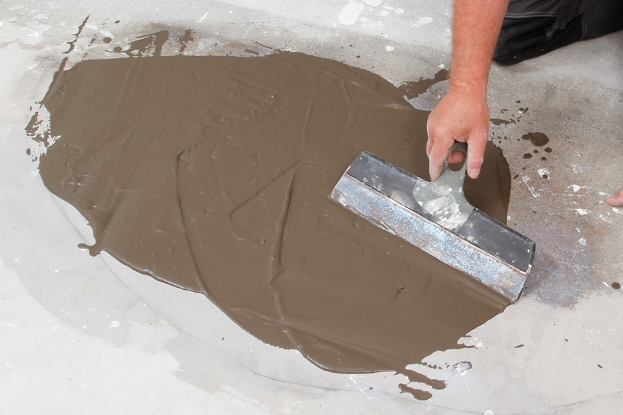 Sådan spartler du et plant betongulv : Fordel spartelmassen jævnt med en bred spartel.
