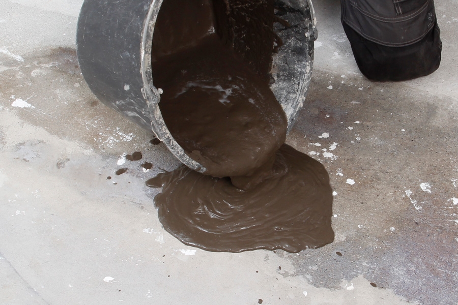 Sådan spartler du et plant betongulv .** Bland gulvspartelmasse med vand, og pisk massen sammen med en boremaskine med et påmonteret piskeris.