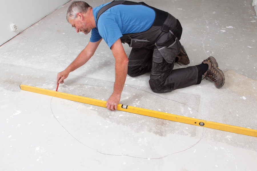 Sådan spartler du et plant betongulv : Brug et langt vaterpas til at tjekke, hvor plant betongulvet er.