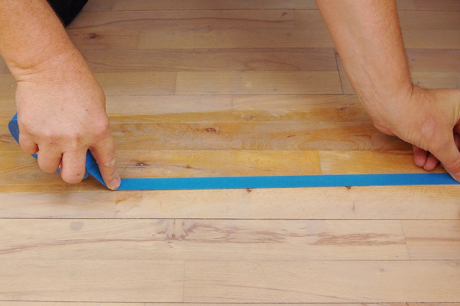 Måla trägolv: Vid golvsocklar, tröskelkanter och andra ställen där det inte ska målas, täcks dessa med målartejp.