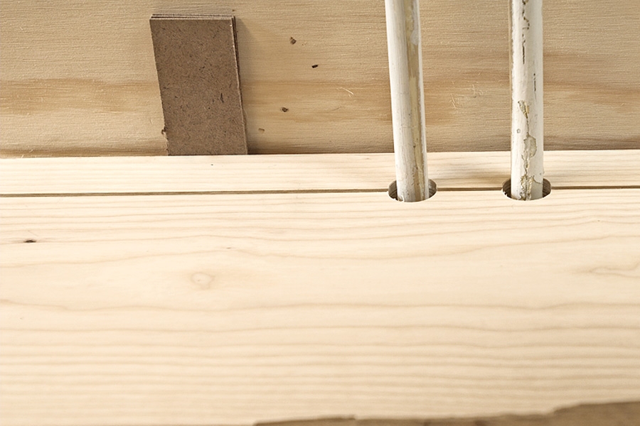 Ilappning mellan två längsgående golvbrädor: Den yttersta brädan läggs på plats med avståndskilar in mot väggen, och nästa bräda slås på plats med ett slagjärn, så att brädan skonas.