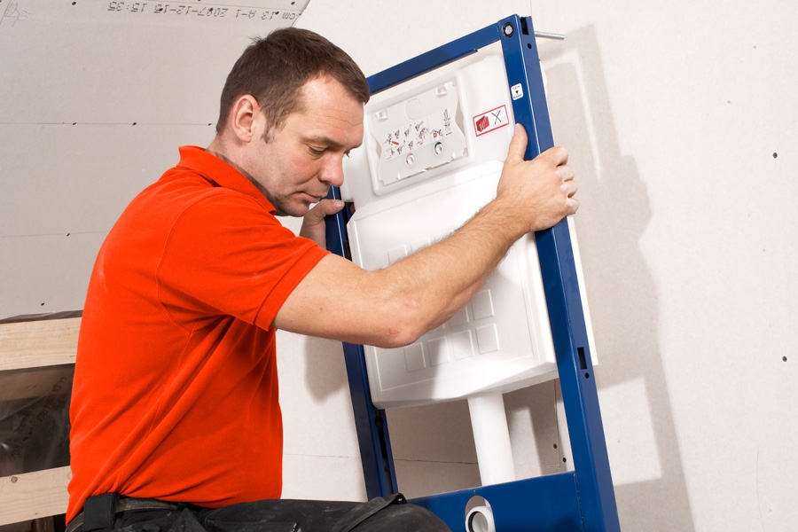 Rammen til toilettet stilles på gulvet og fastgøres til væggen i toppen.