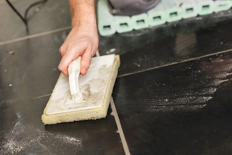 Asenna uusi laatta: Poista ylimääräinen saumalaasti vetämällä laattasientä viistosti saumojen yli.