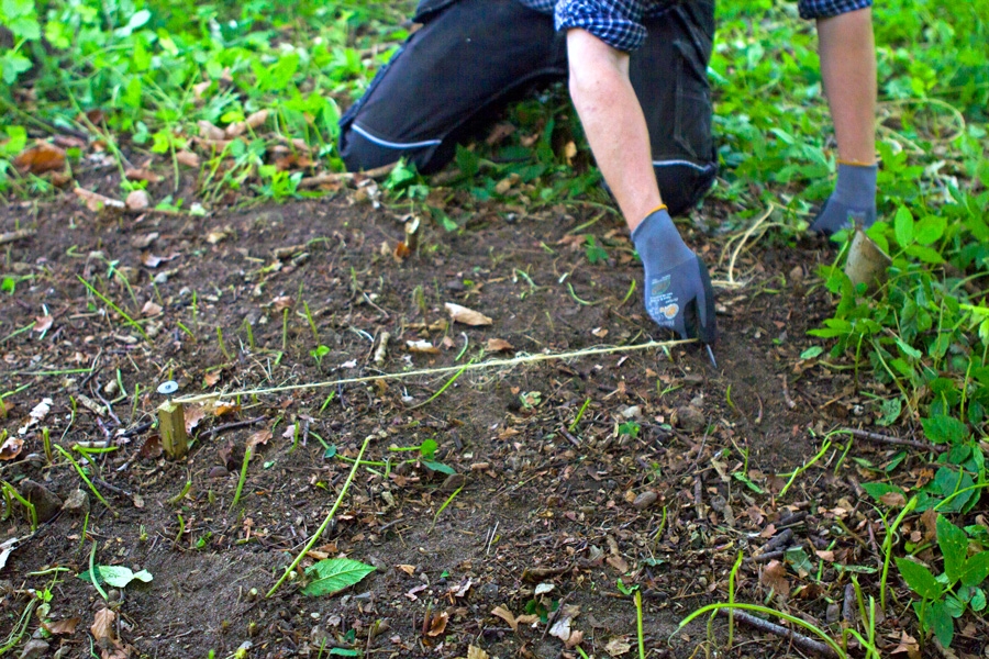 Merkitse tulisijan paikka linjalangalla. Periaate selitetään tarkemmin alempana. Merkitse nurkkien paikat kivillä tai kepeillä.