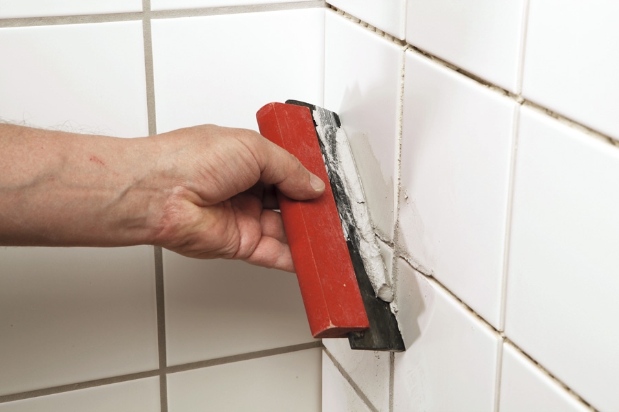 Fugemasse fliser: Fugemassen trekkes utover flisene i skrå bevegelser med en gummisparkel eller et gummikledd fugebrett.