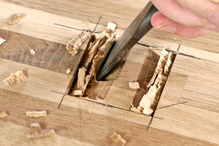 Stämjärn: “Stäm” först lodrätt med den platta sidan av stämjärnet - 1 mm innanför markeringen. Vänd sedan stämjärnet med den platta sidan nedåt och hugg snett ut mot kanterna. Fortsätt genom träet.