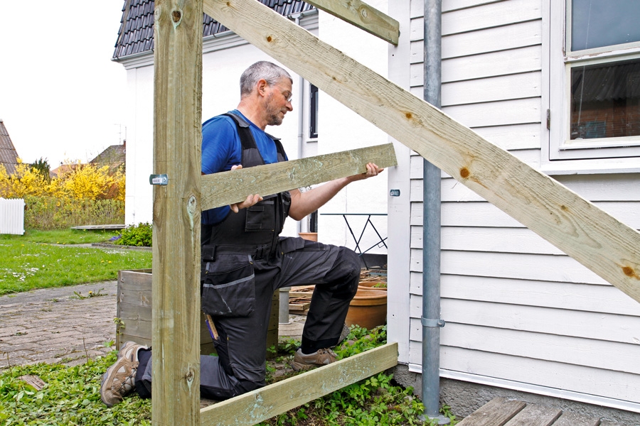 Om det finns något stadigt i närheten (här är det ett hus) kan det vara lönt att fästa stolpen vid det. Annars fästs ännu en snedsträva vid stolpen, vinkelrätt mot den första.