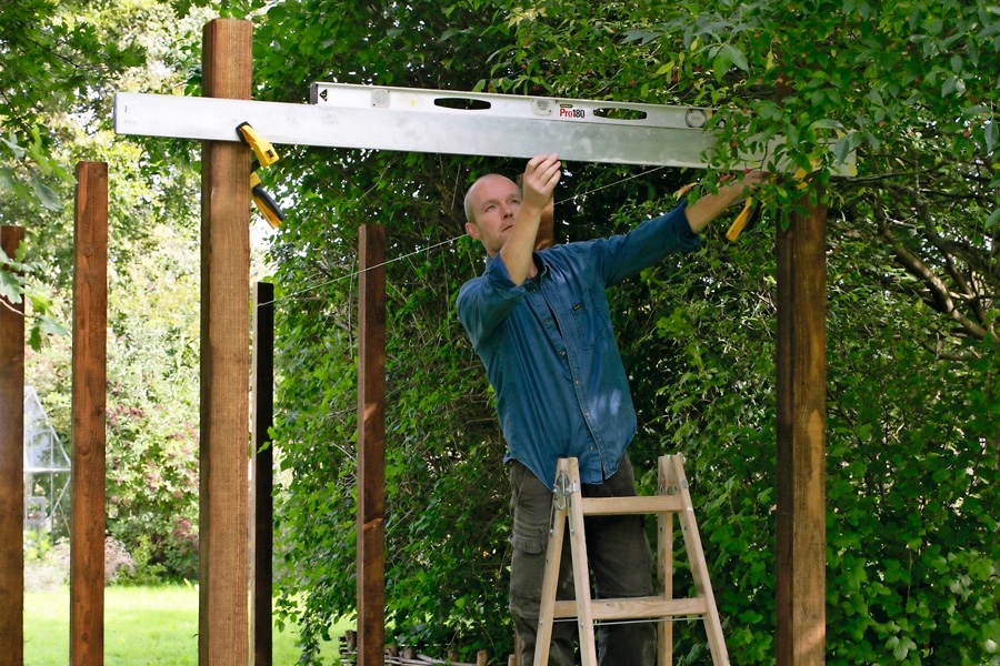 För att försäkra sig om att stolparna står lodrätt medan man bygger färdigt, bör man fixera dem genom att skruva fast snedsträvor från botten av en stolpe till toppen av den som står bredvid.