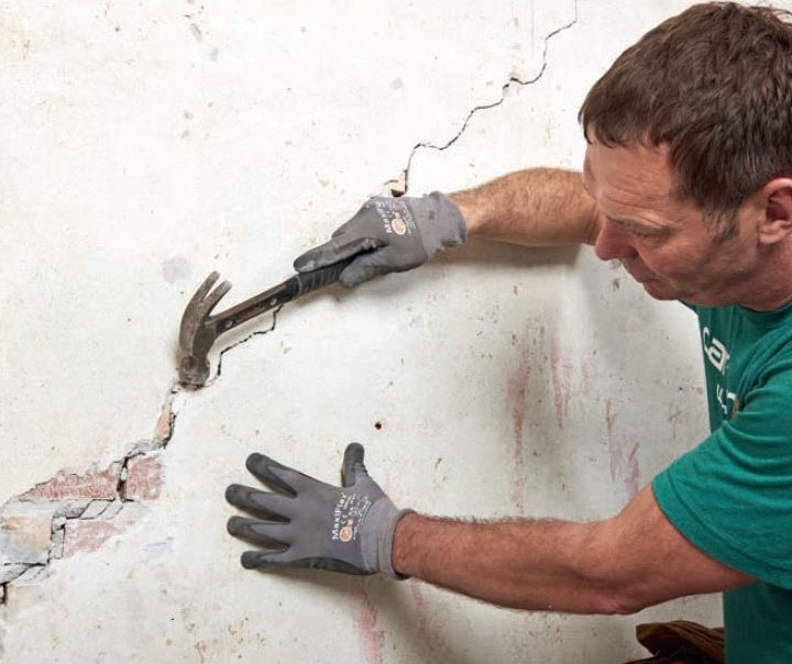 Sättningar i hus: Putsen knackas bort runt sprickan