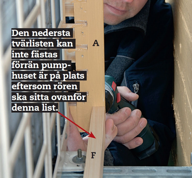 Den nedre tvärlisten på värmepumpsskydd vilar på de två stålkonsolerna som luftvärmepumpen står på