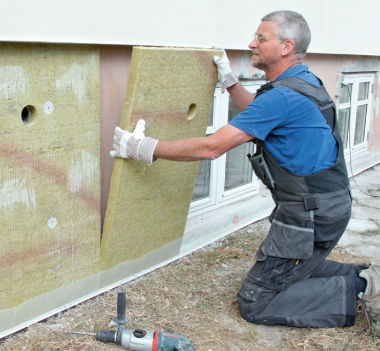 Isolasjonen til isolering av grunnmur trykkes fast på grunnmuren