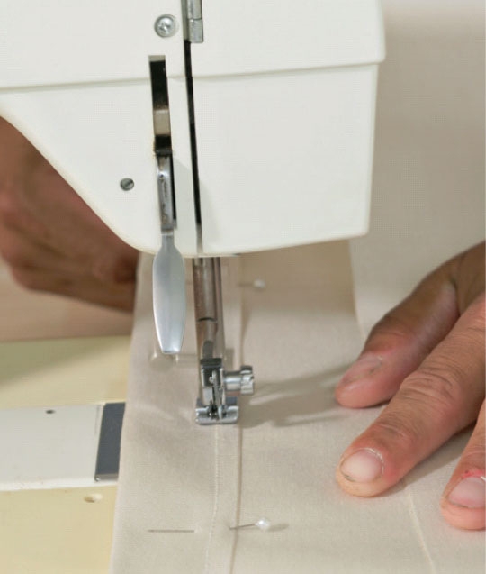 Seilduk: Bøy en 3 cm bred søm langs to av kantene, sett i nåler, og stryk sømmen før du syr 2,5 cm fra kanten.