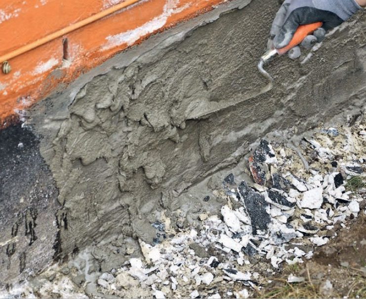 Pudsning af sokkel: Mørtlen kastes på væggen i små klatter