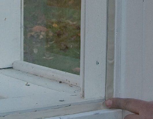 Kitt glattes ut med en finger i ruten i orangeri