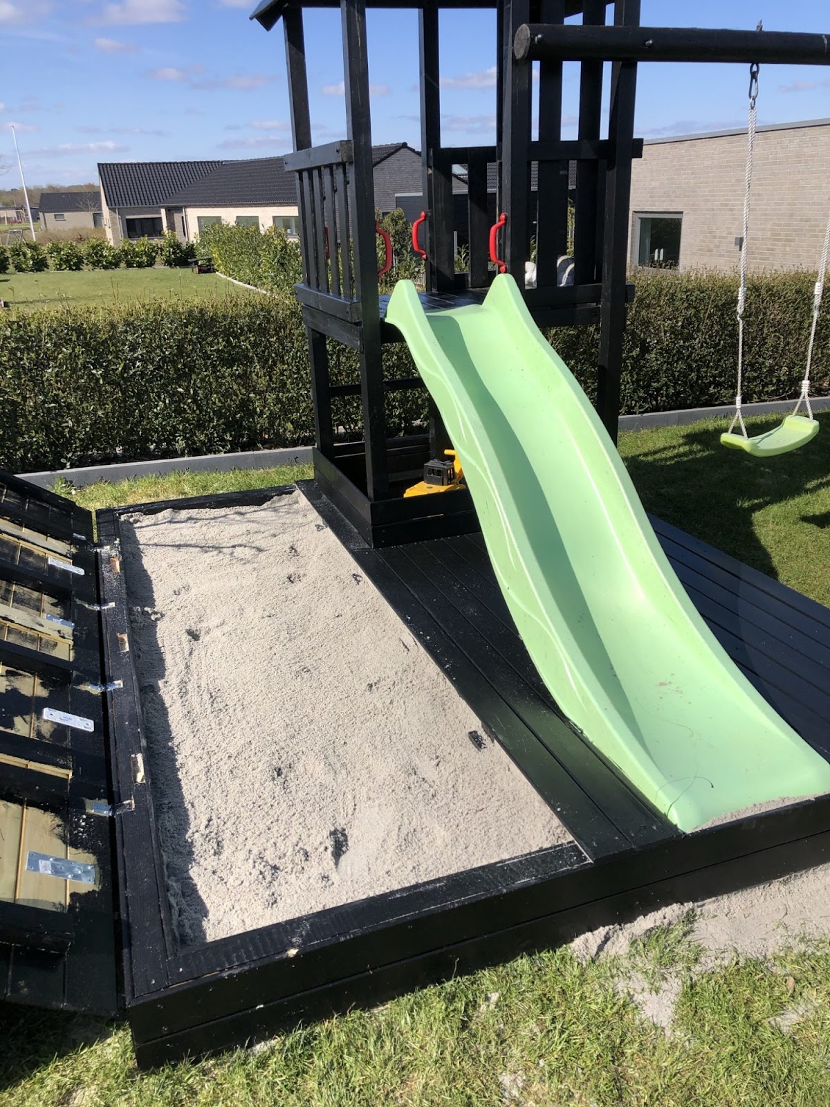 Skjult sandkasse omkring gyngestativ