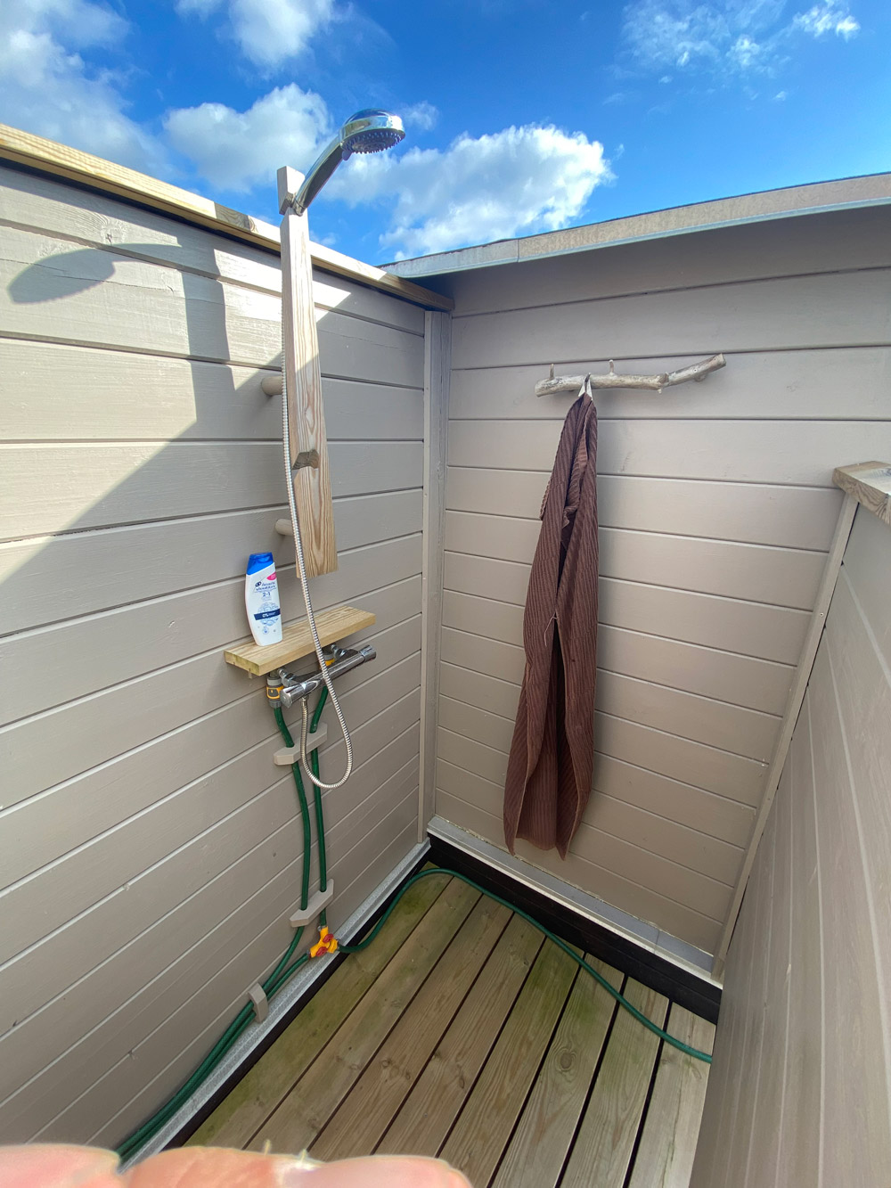 Udendørsbrusebad med solopvarmet vand og genbrugsmateriale