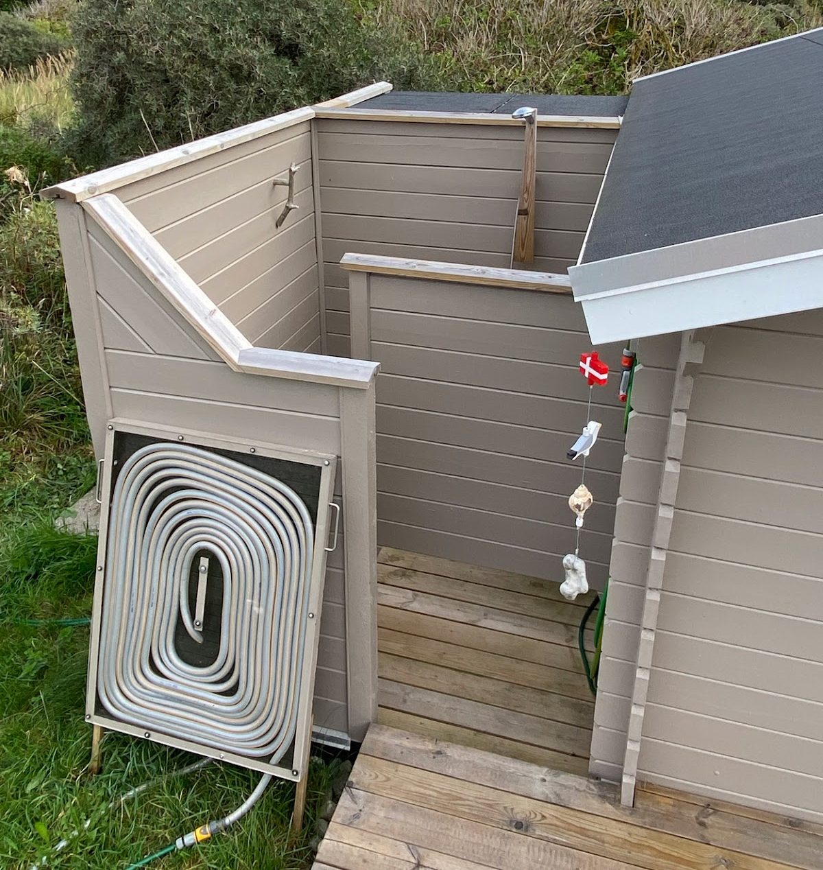 Udendørsbrusebad med solopvarmet vand og genbrugsmateriale