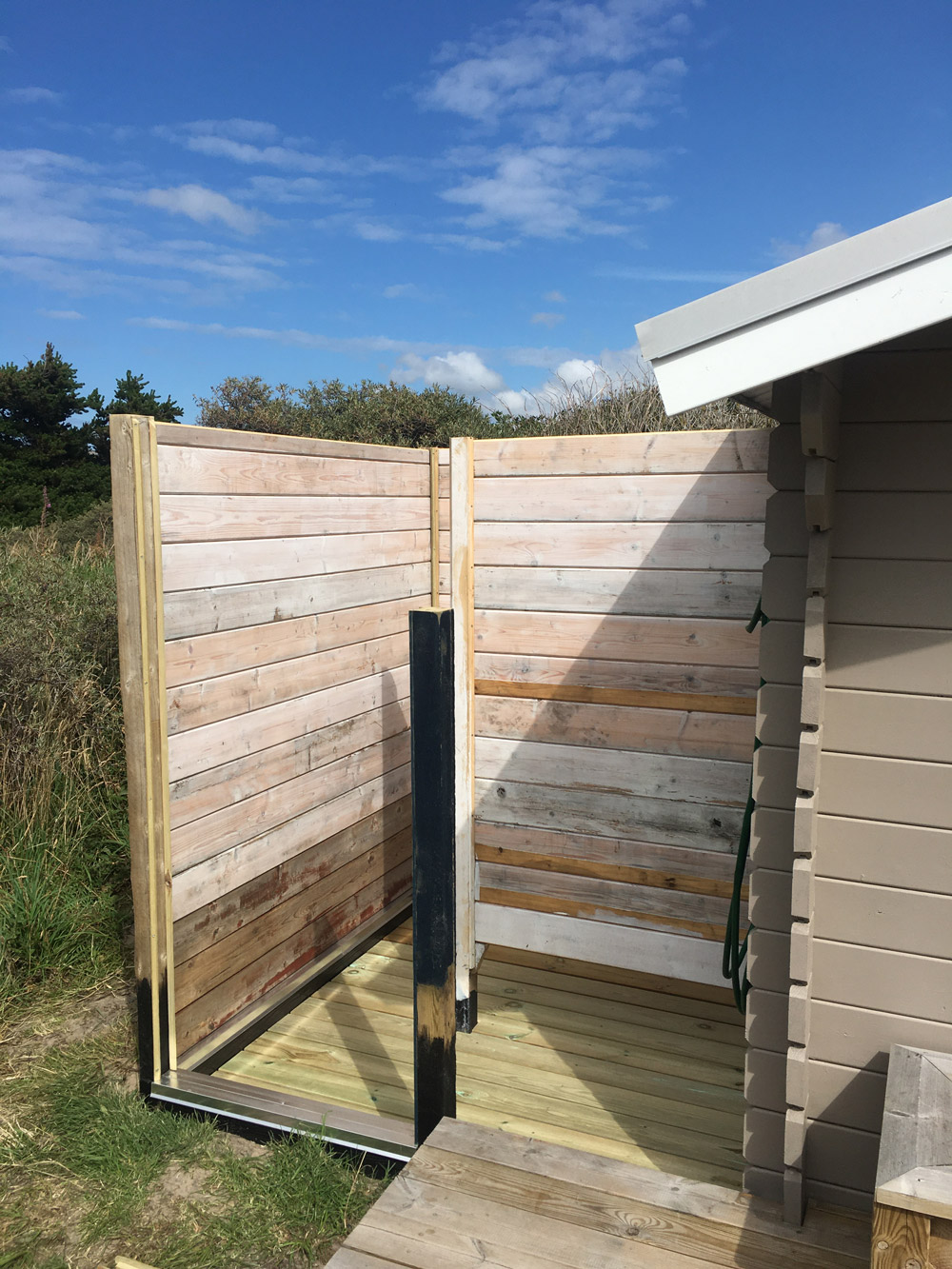 Udendørsbrusebad med solopvarmet vand og genbrugsmateriale