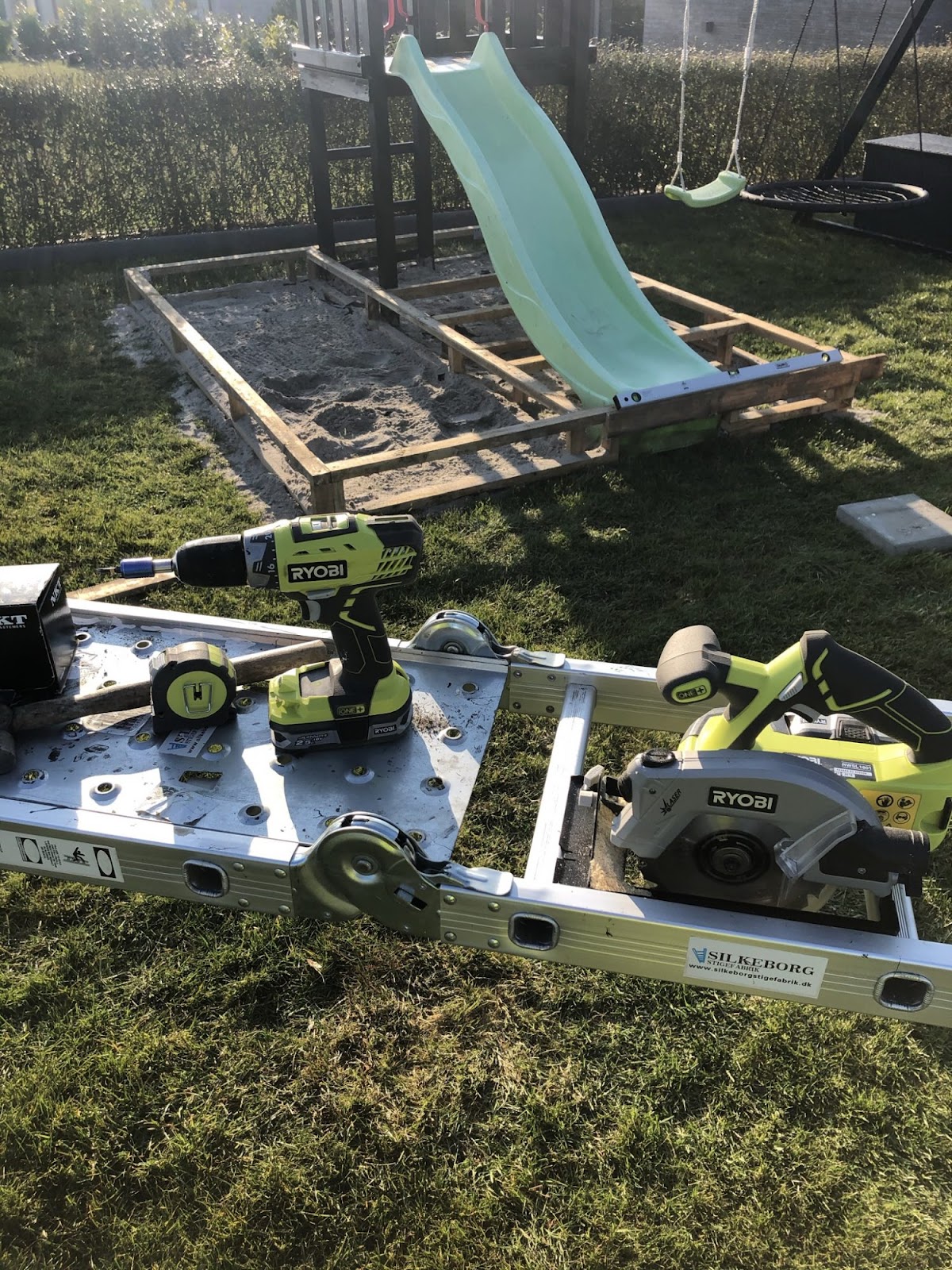 Dold sandlåda runt gungställning