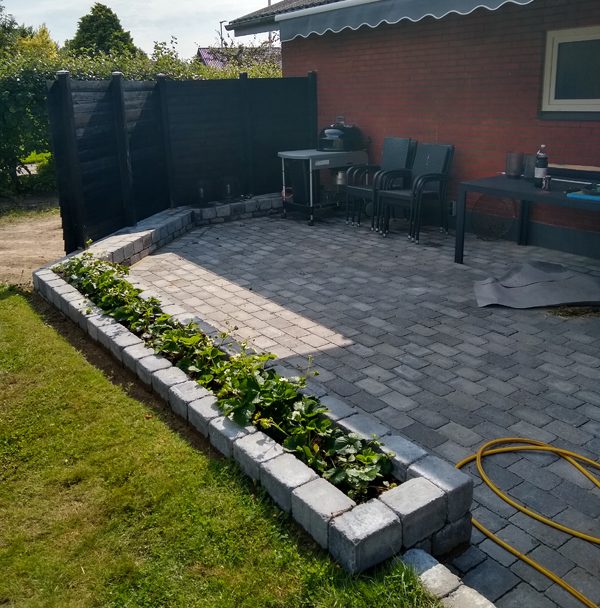 Fliseterrasse med læskærm og bed