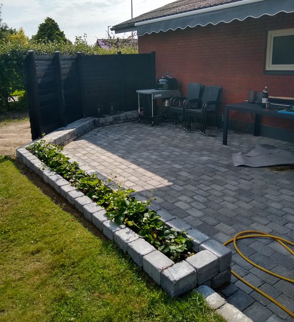 Stenterrass med vindskydd och rabatt