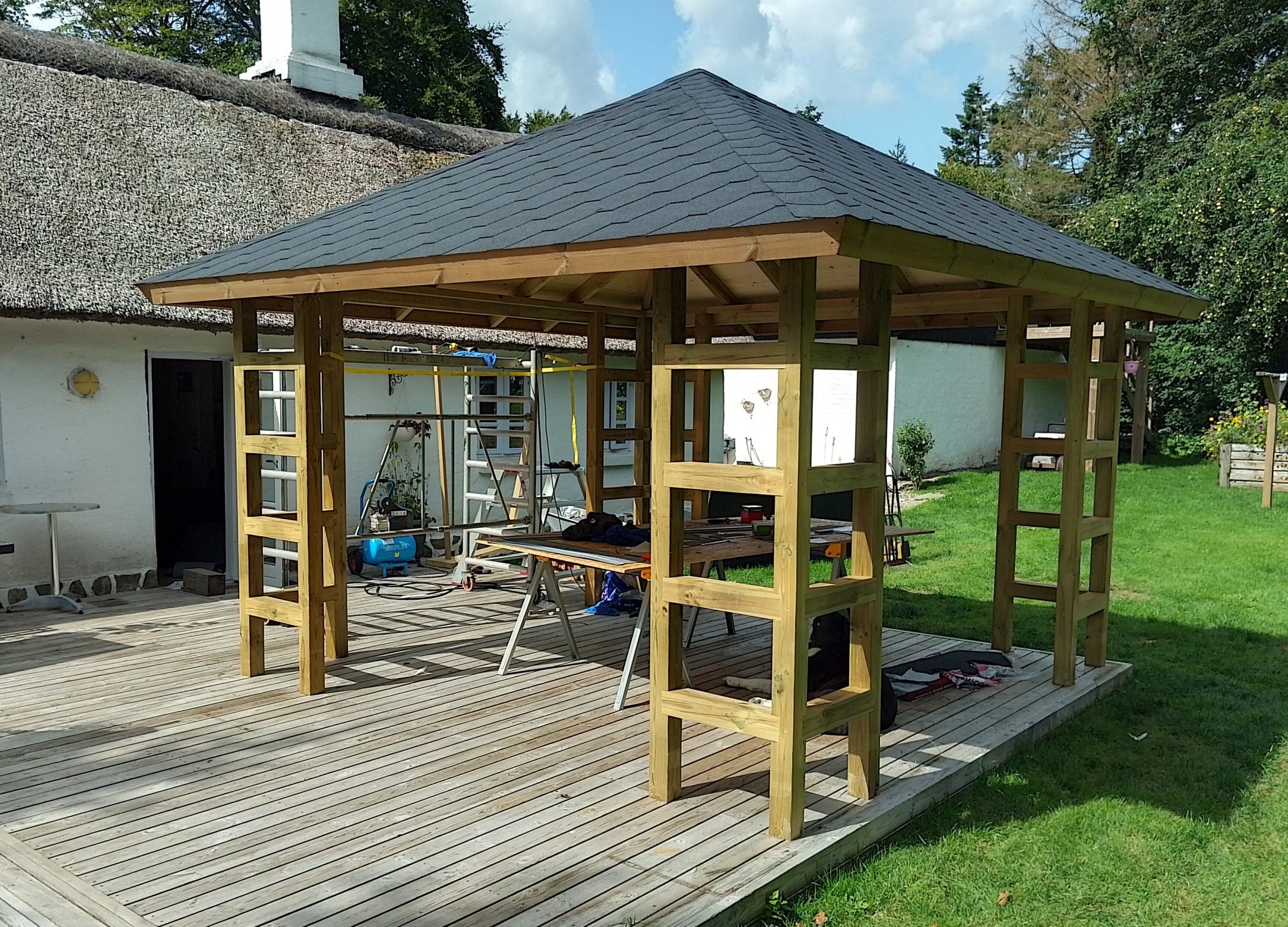 Paviljong av grovt virke med shingeltak