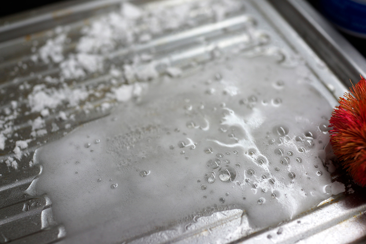 Rengöring av bakplåten med vatten, bakpulver och ättika.