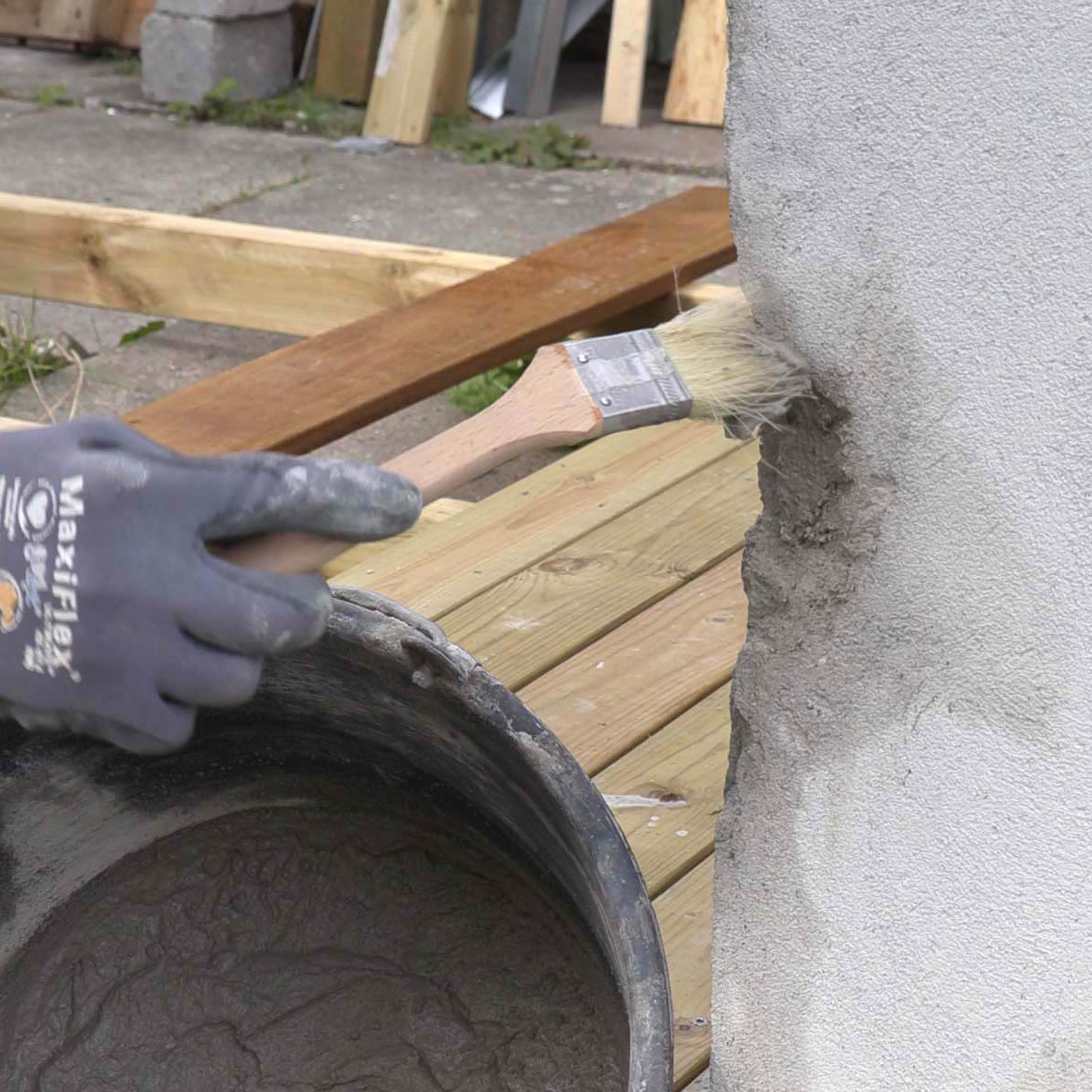 Ødelagt hjørne på pusset murvegg: Pensle et tynt lag mørtel på reparasjonsstedet