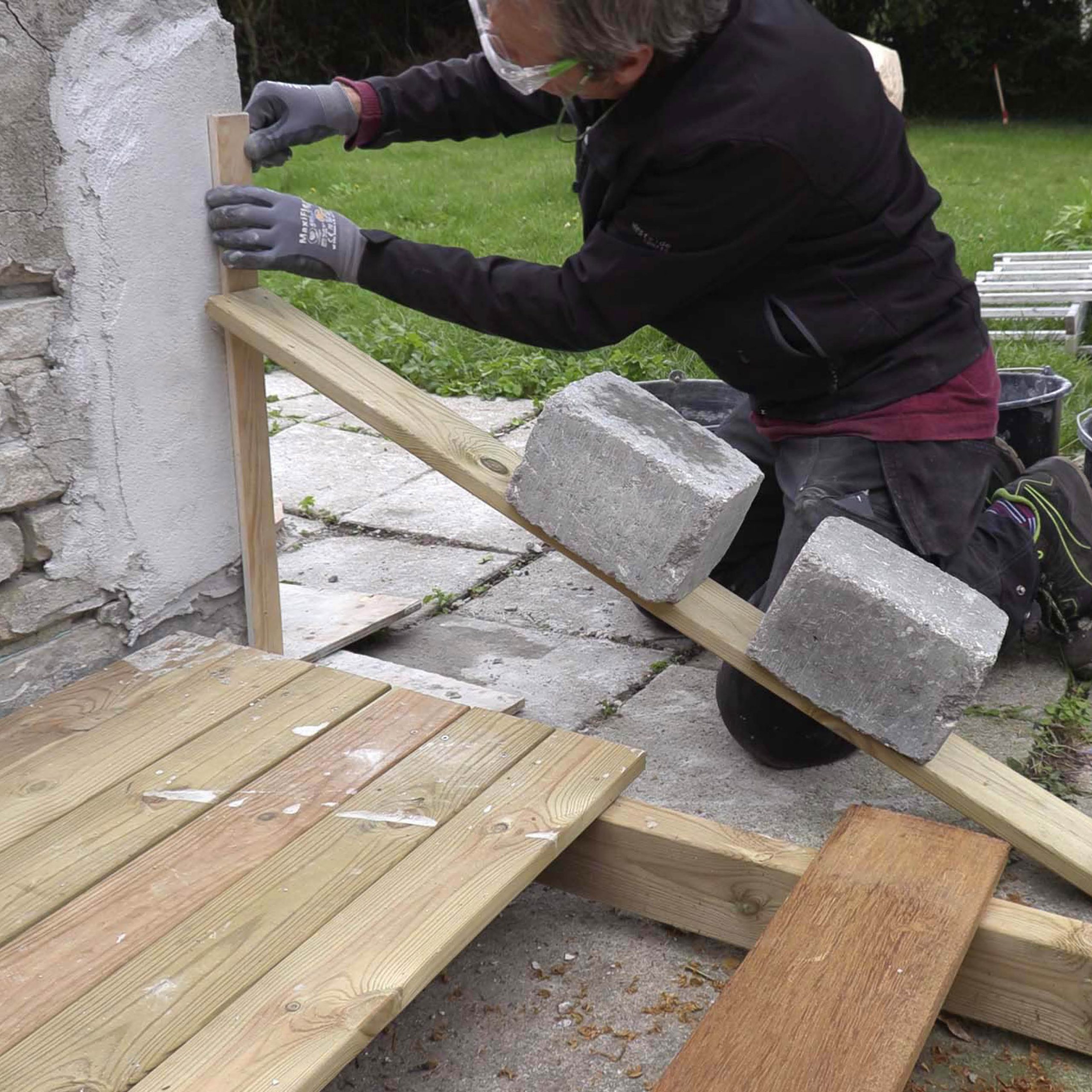 Ødelagt hjørne på pusset murvegg: Et skrått bord holder det loddrette bordet