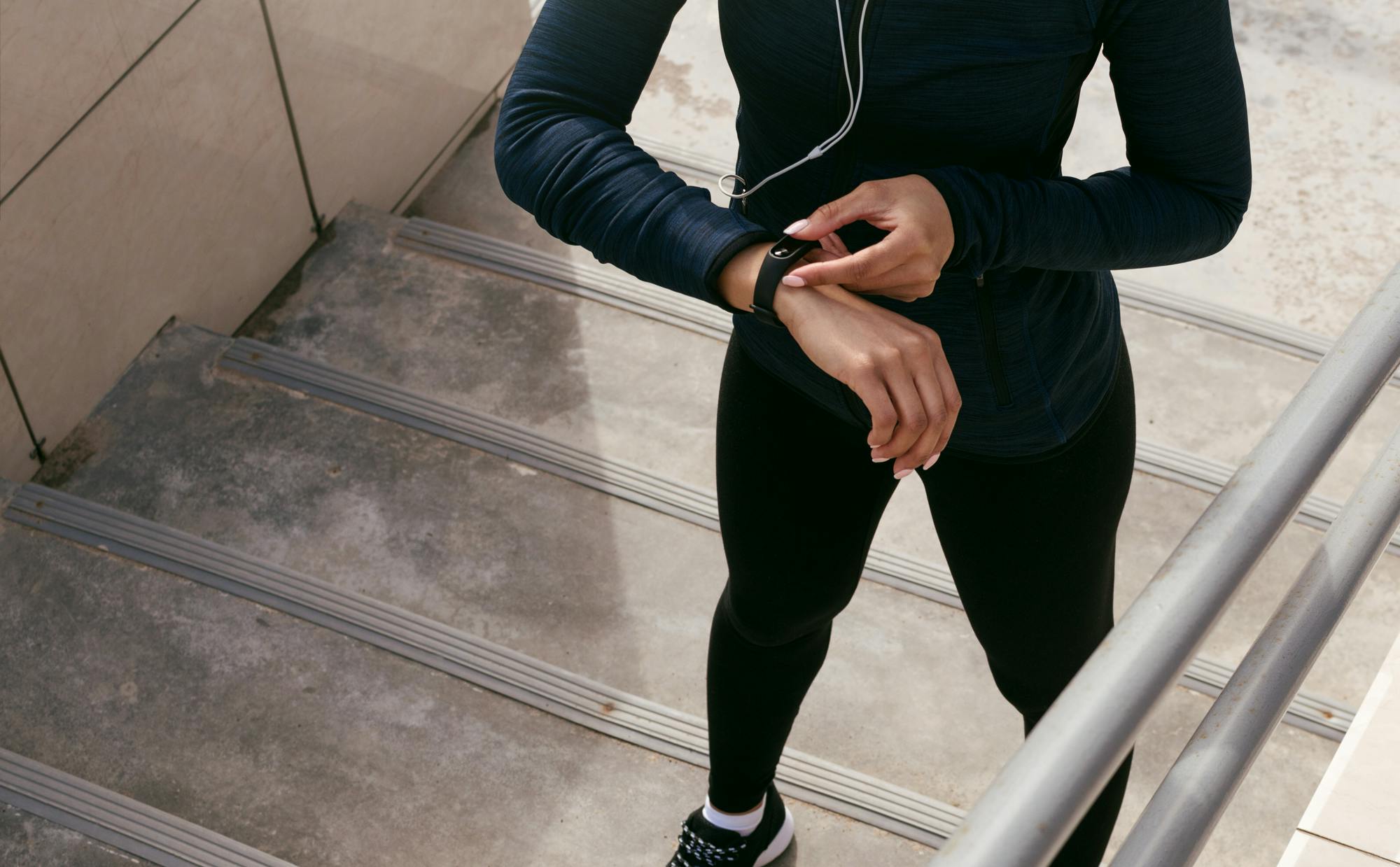 Kvinna i trappa tittar på sitt aktivitetsarmband